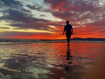 Silhouette man standing on beach during sunset