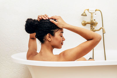 Shirtless woman resting in bathtub at home