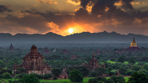 Panoramic view of temple and buildings against sky during sunset