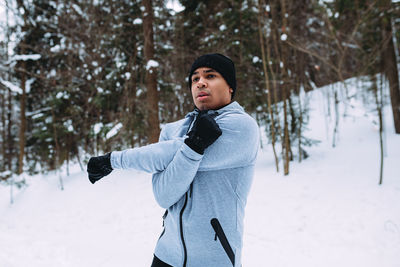 Young man exercising while wearing warm clothing during winter