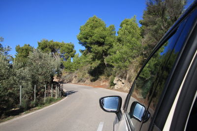 Road amidst trees against clear sky seen through car windshield