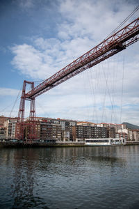 Cranes by river against sky in city