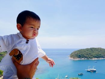 Cute boy looking at sea against sky