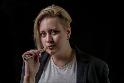 Close-up portrait of young woman against black background