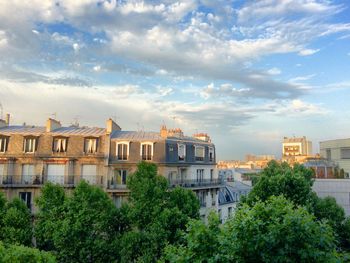 Buildings in city against cloudy sky