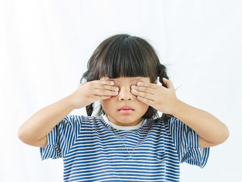 Portrait of teenage girl covering face against white background