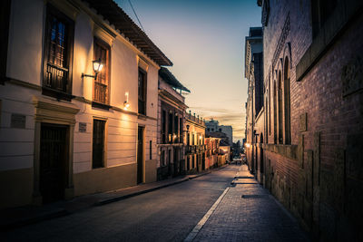 Empty alley amidst buildings in city at night