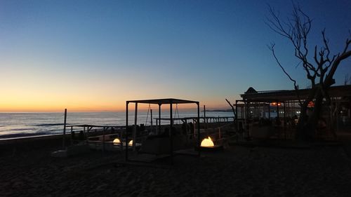 Silhouette people on beach against clear sky during sunset
