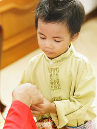 Cropped image of father holding son hand at home