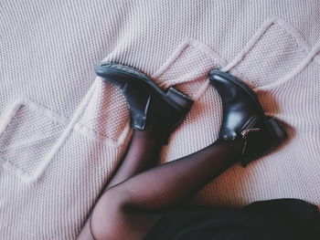 Low section of woman in high heels lying on bed