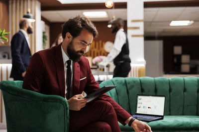 Side view of man using laptop while sitting in office