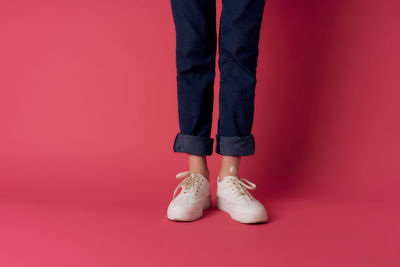 Low section of woman standing against red background