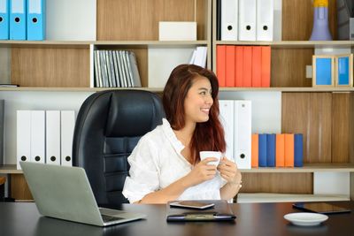 Young woman using phone while sitting on table