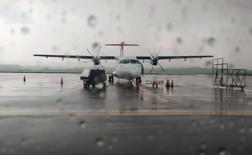 Airplane at airport runway against sky