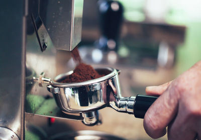 Cropped hand of man making coffee in cafe