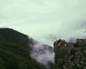 People on cliff against sky