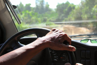 Cropped hand of person driving car outdoors