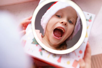 Reflection in the mirror of a christmas caucasian girl in santa's cap.