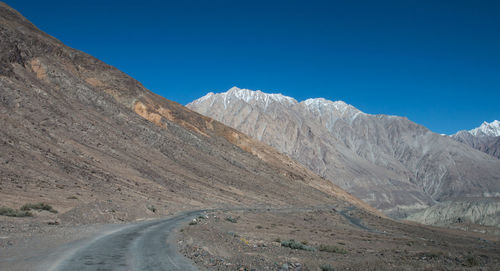 Road amidst mountains against clear blue sky