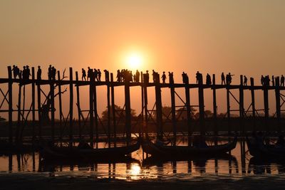 Silhouette boats moored in sea against orange sky