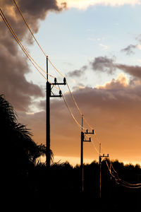 Low angle view of silhouette electricity pylon against sky during sunset