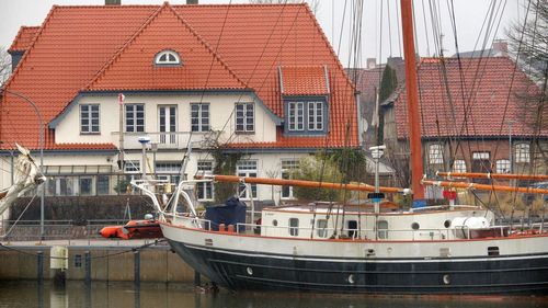 Boats moored at harbor against sky