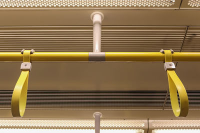 Close-up of yellow metal railing against wall