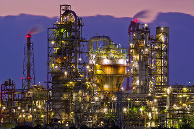 Illuminated factory against sky at night