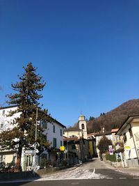 Street amidst buildings against clear blue sky