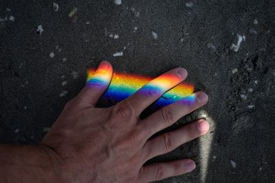 Rainbow on hand of man at beach