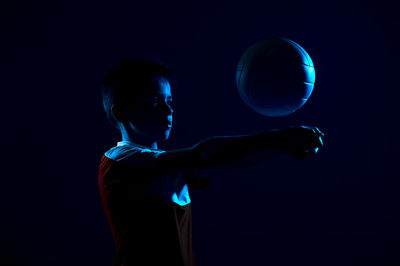 Boy playing with volleyball in darkroom