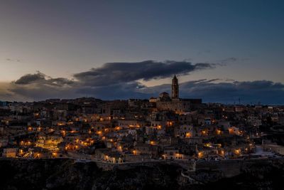 Illuminated buildings in city against sky at dusk