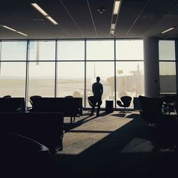 Rear view of man standing in waiting area of airport