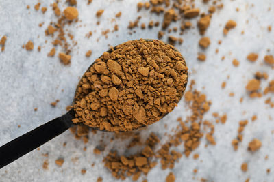 Small spoon with instant coffee granules above grey stone table in light studio