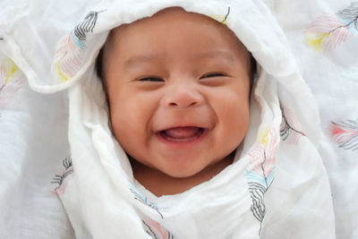 Portrait of cute baby girl lying on bed