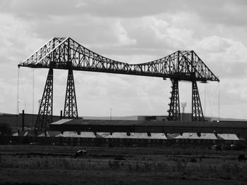 Tees transporter bridge by field against sky at middlesbrough