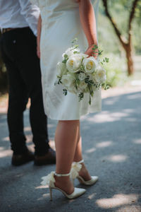 Low section of woman holding bouquet