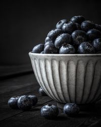 Close-up of fruits in bowl on table against black background
