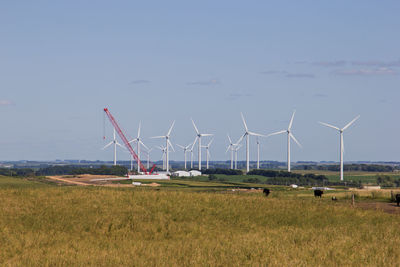 Windmills on field against sky