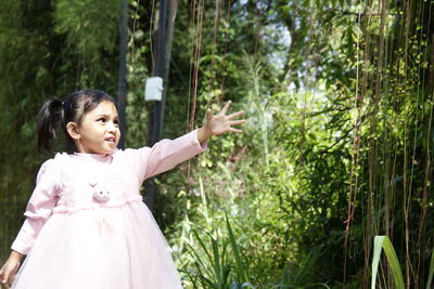 Young woman standing against trees in forest