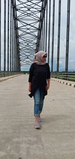 Rear view of woman standing on bridge