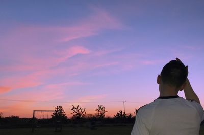 Rear view of silhouette man standing against sky during sunset