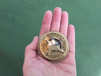 Cropped hand holding navigational compass over table