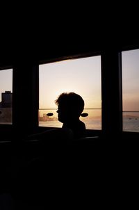 Rear view of silhouette man looking through window