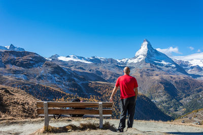 Rear view of man standing on snowcapped mountain