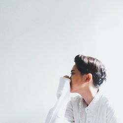 Side view of thoughtful young woman against white background