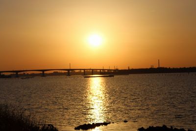 Silhouette bridge over river against sky during sunset