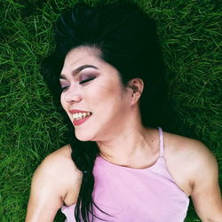 Close-up of smiling young woman lying on grass