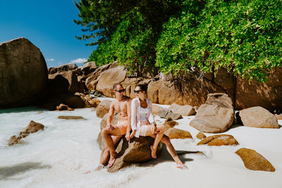 Couple sitting on rock at beach