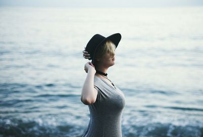 Boy standing in sea against sky